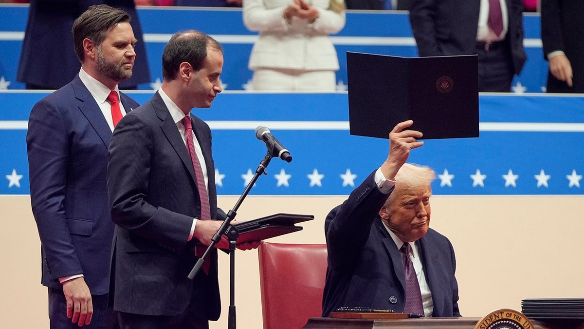 President Donald Trump signs executive orders on the stage