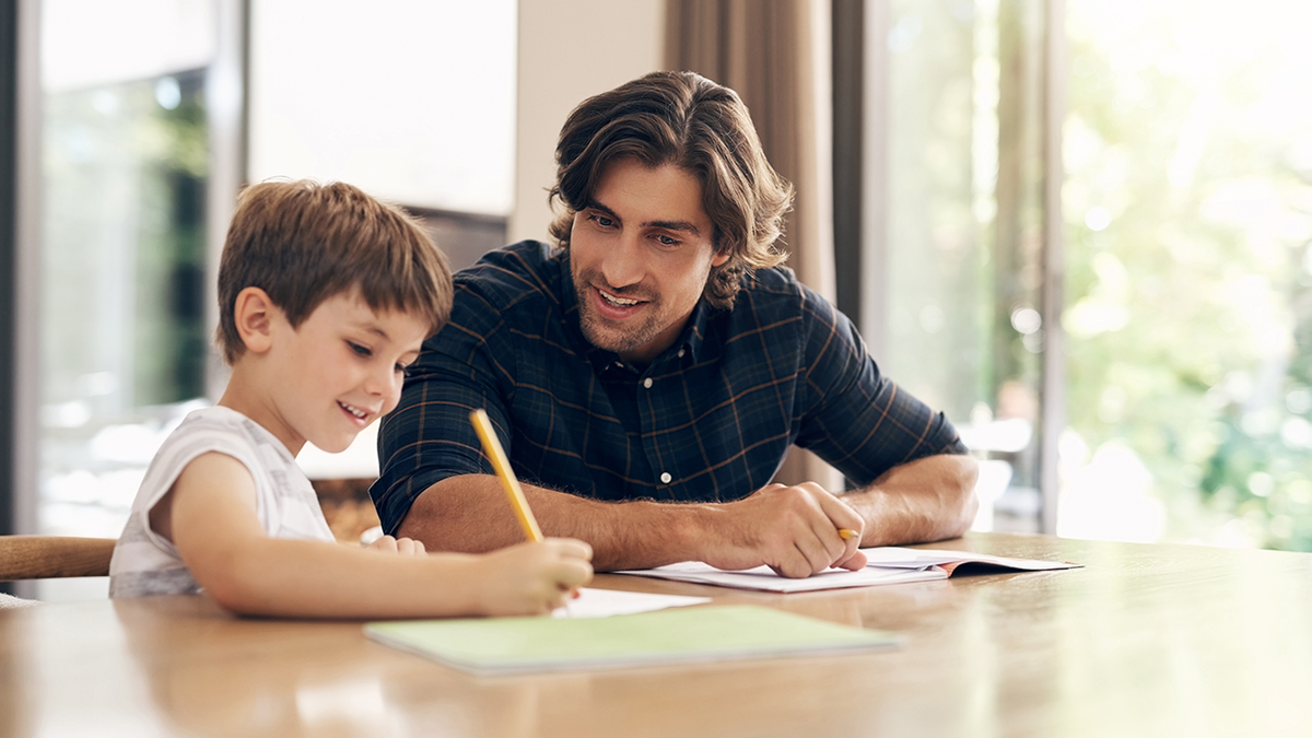 Dad helps the son on the handwriting