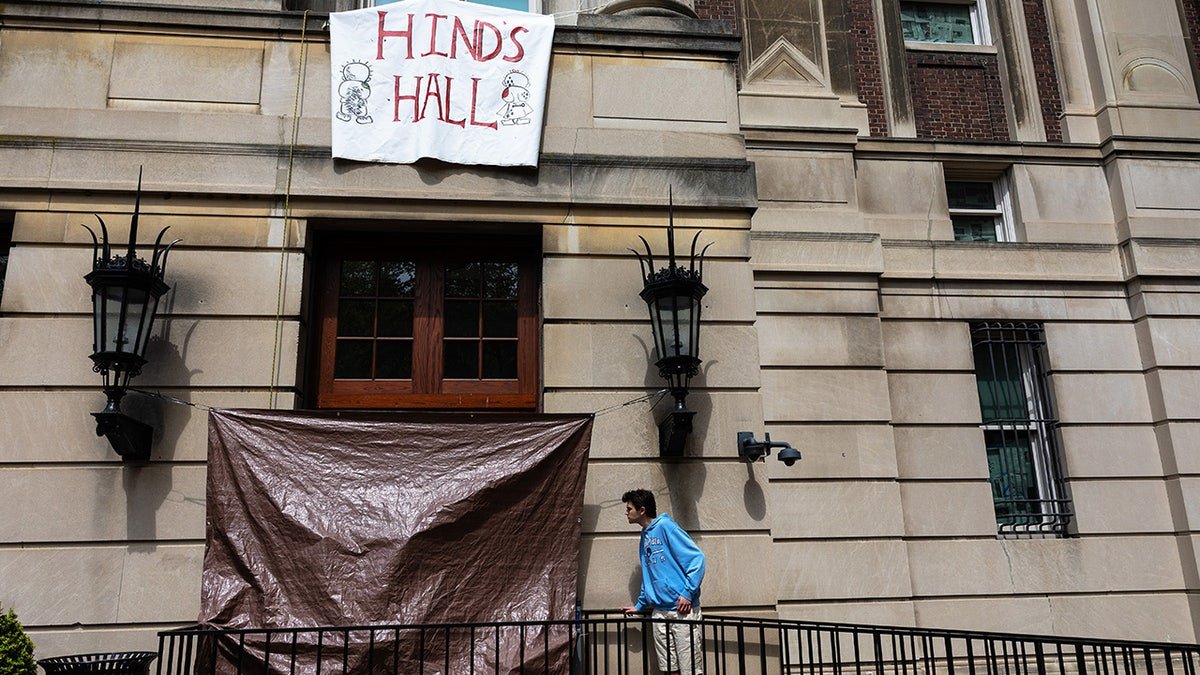 A student in Colombia is looking for the damage of the door windows in Hamilton Hall at Columbia University
