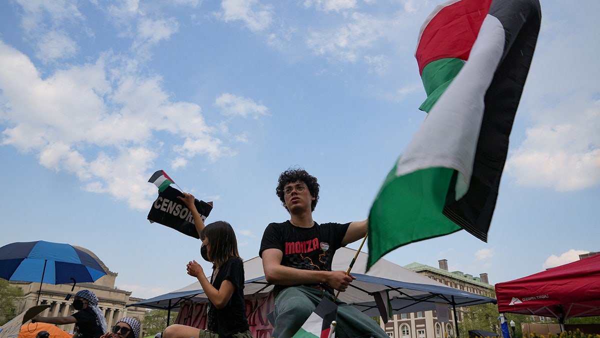 The protesters carry the Palestinian flag while students gather on the campus of Columbia University