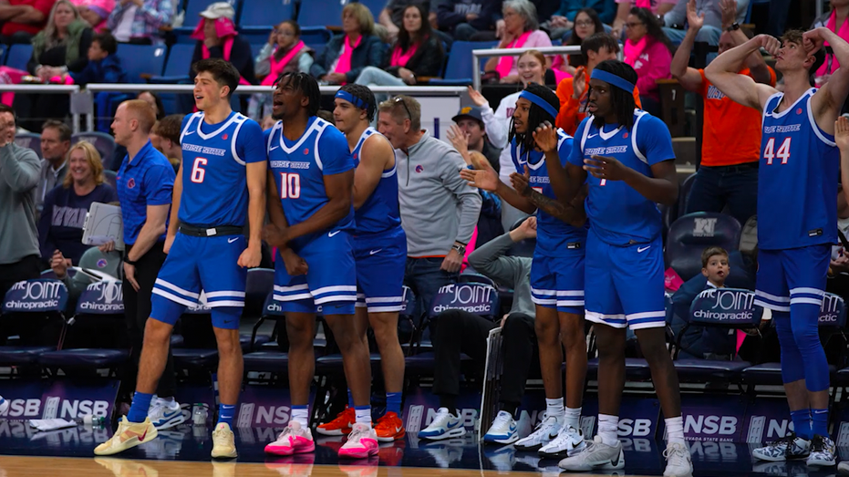 A group of men stare in the same direction on the basketball field.