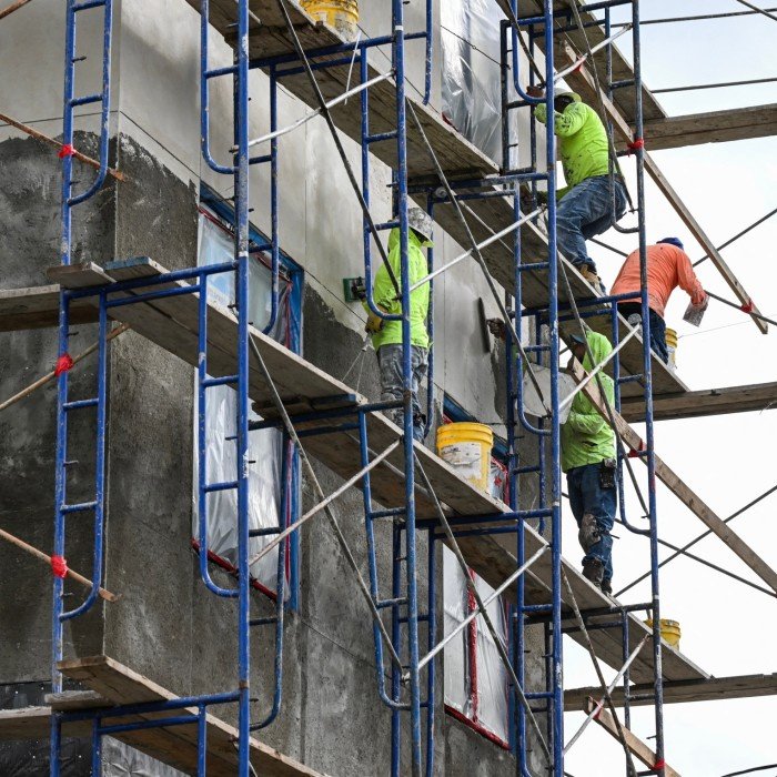 Building workers stand on the scaffolding
