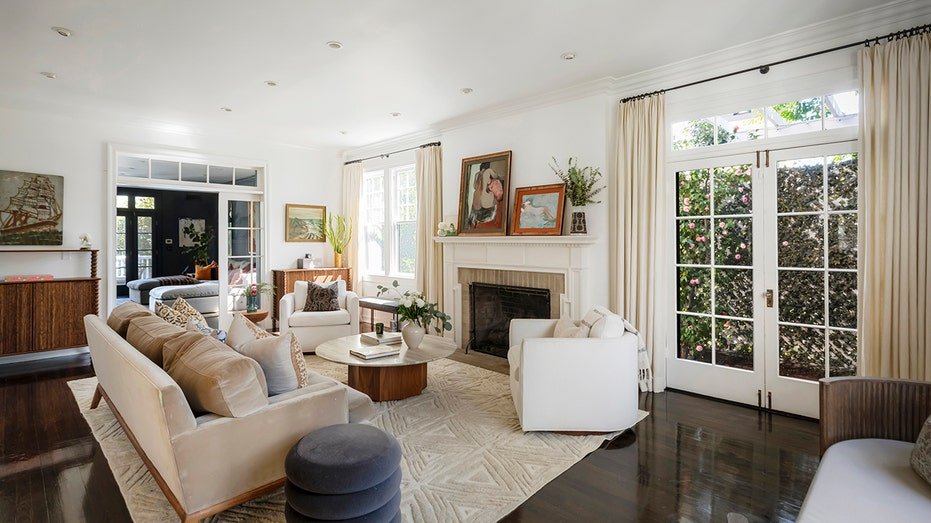 The living room has dark floors of solid wood, a stone fireplace and a door that leads to annihilation.