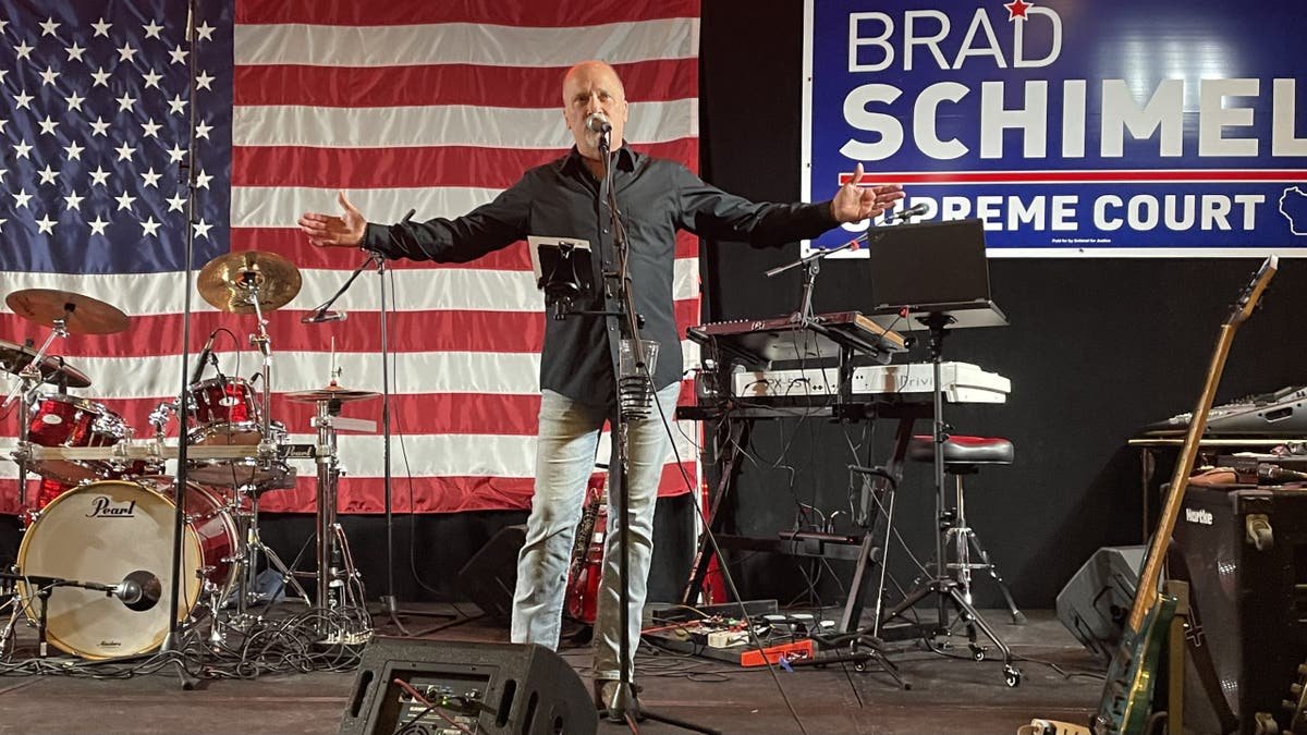 Brad Shimel on stage, the flag behind him