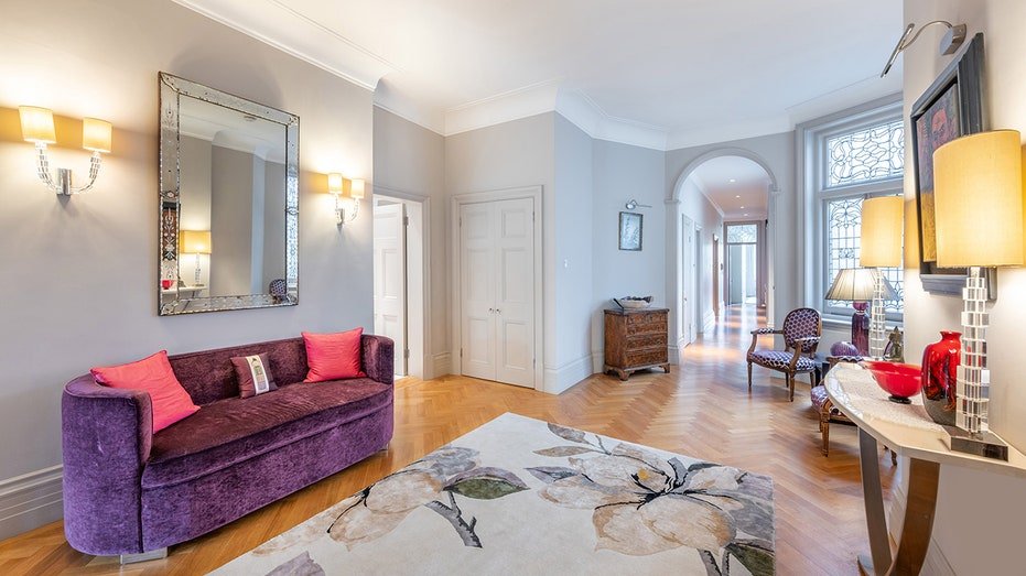 The entrance is characterized by solid wood floors with a floral and purple sofa.