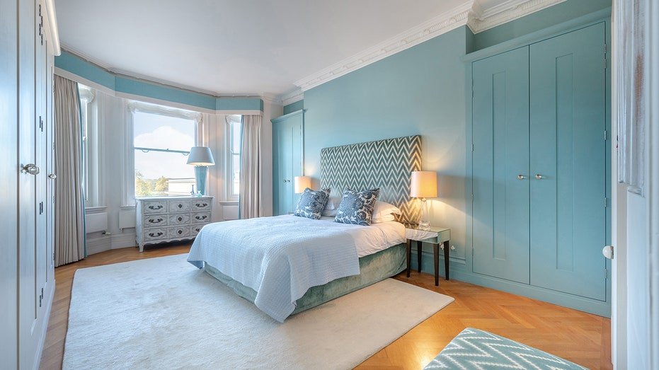 The primary bedroom has blue walls and a large white carpet.