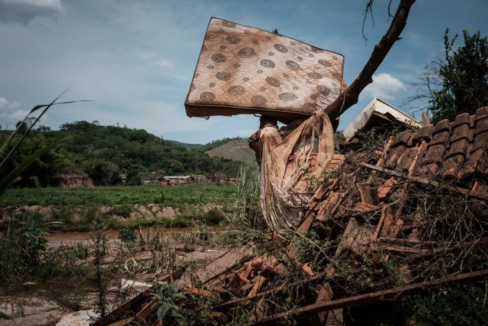 A damaged house is covered with a collapsed ceiling in the debris and plants. It is presented in a tree over the rubble