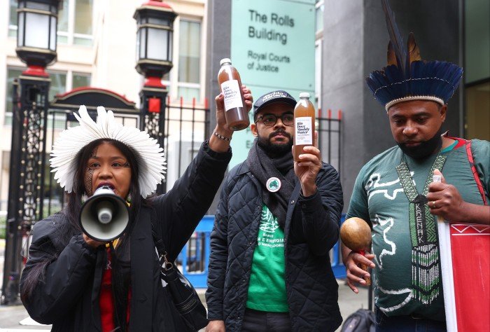 The protester speaks to loudspeakers, while others carry bottles with the name