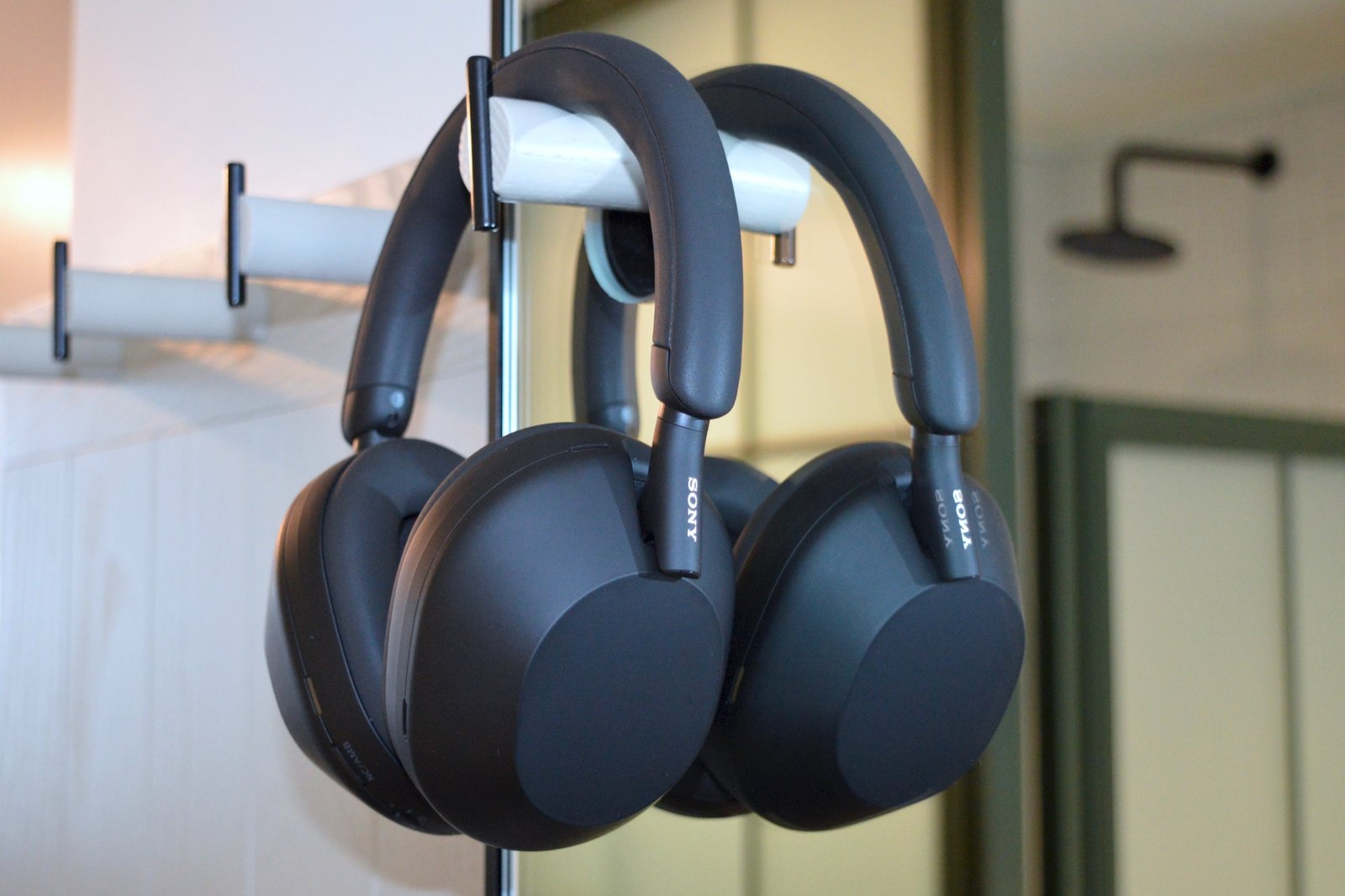 Sony Wh-1000xm5 wireless headphones hang on the wall hook in front of the mirror.