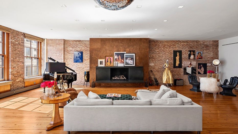 The living room features an open brick walls with a high fireplace on a wooden wall.