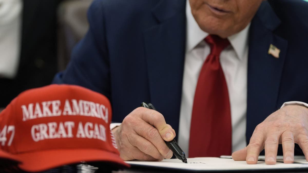 Trump signed EO with the red Maga hat on the office