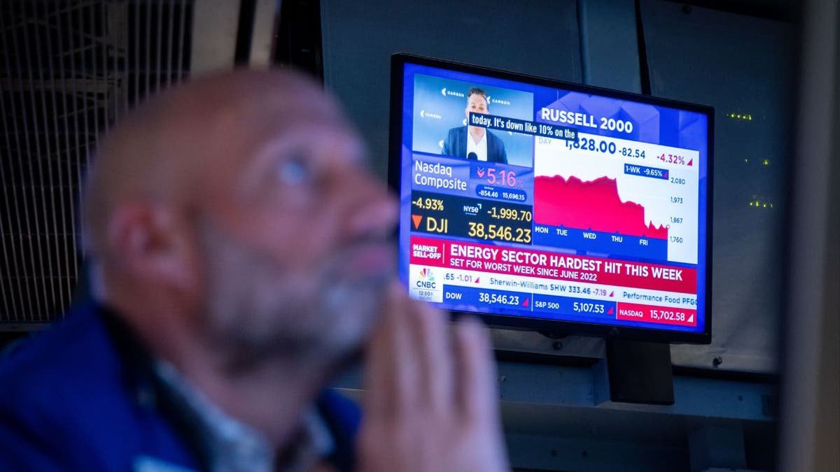 A man watching television screens that display news reports on the stock market