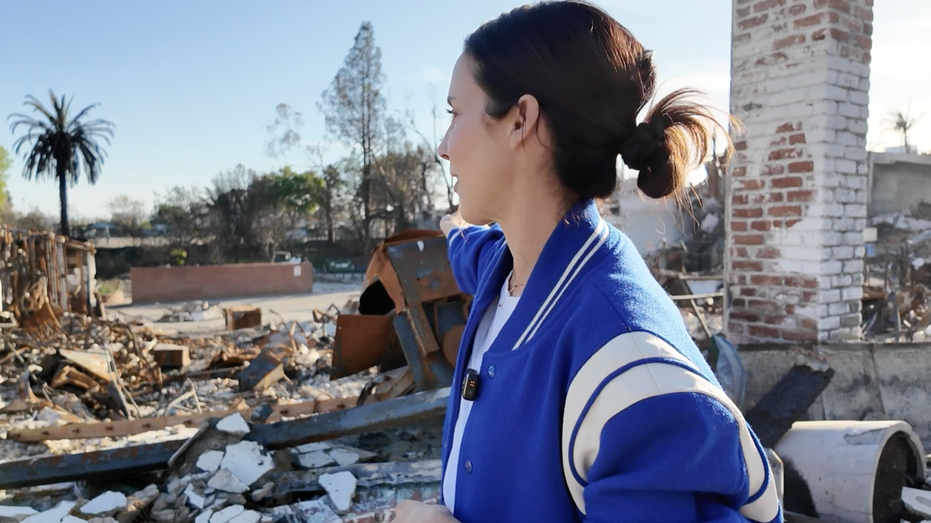 A woman looks at a store destroyed by fire.