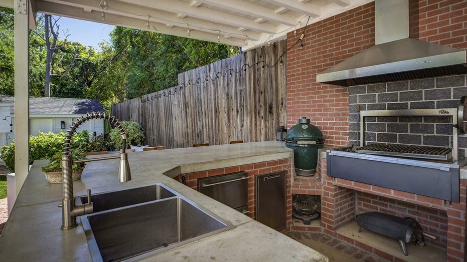 The backyard also features an outdoor kitchen with barbecue and a barr.