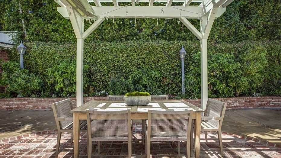 The backyard is characterized by an outdoor food area under a white courtyard.