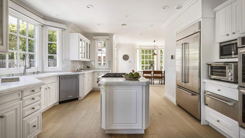 The kitchen features all stainless steel devices and a large medium island.