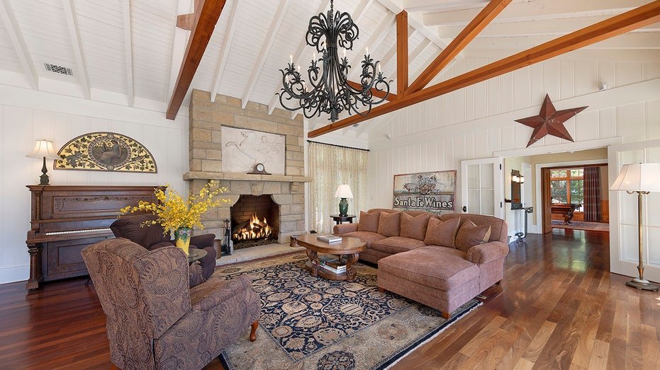 The great room features exposed wooden beams on the ceiling and a burning fireplace.