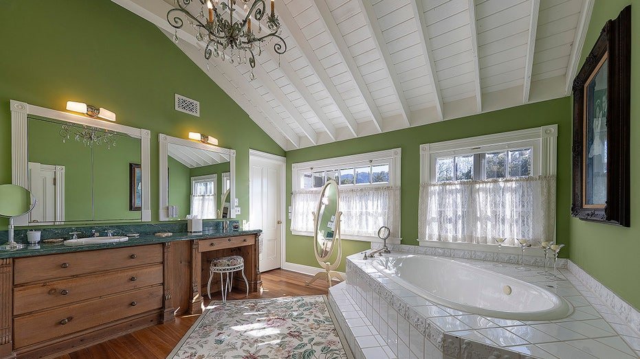 One of the inner bathrooms is characterized by green walls, large vanity and bathtub.