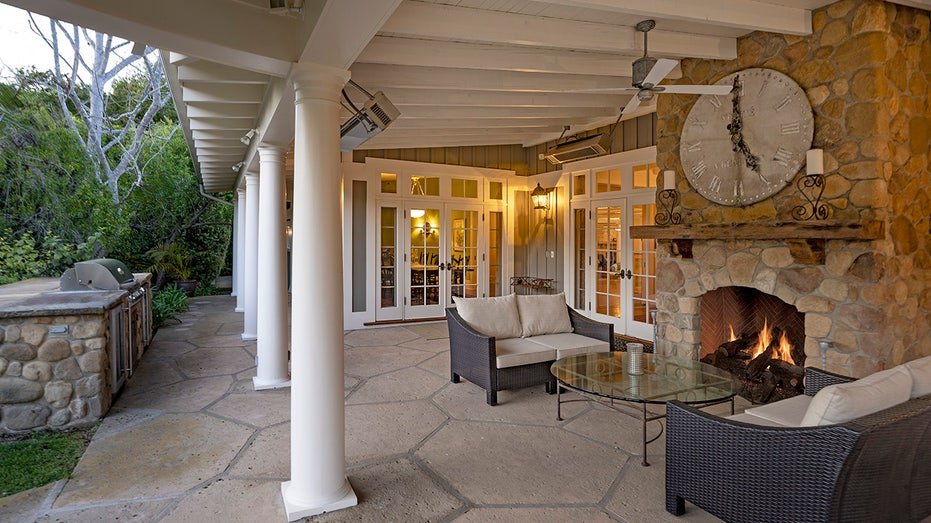The backyard is characterized by an outdoor living room with a fireplace and an outdoor kitchen.