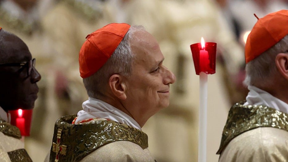 Cardinal Robert Francis Brevost carries a candle during Easter Mass