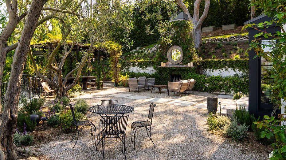 The backyard is characterized by a wood flipping fireplace with a seating area in front of it.