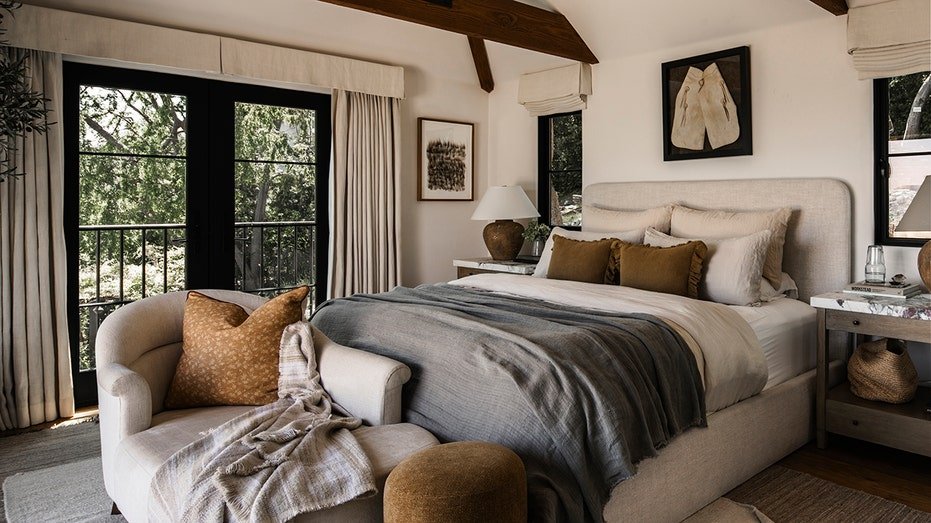 The basic bedroom features exposed wooden ceilings, hard floors and many windows.