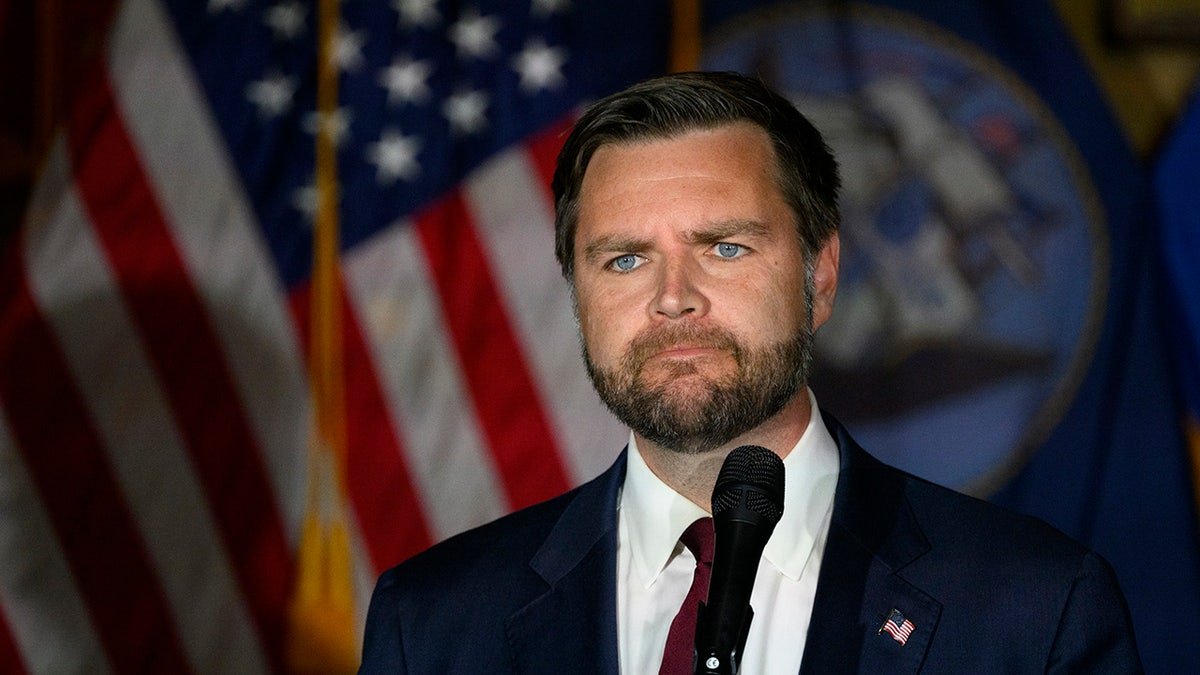 JD Vance stands in front of the American flag