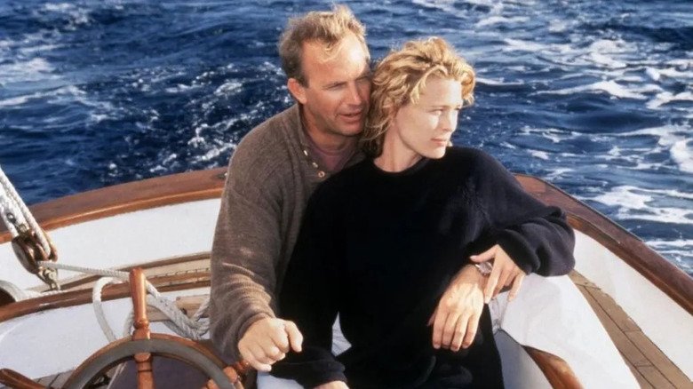 Garrett (Kevin Costner) is sitting behind the Teresa (Robin Wright), one arm around her waist and the other holds a sailboat wheel, in the middle of the ocean in a scene of a message in a bottle