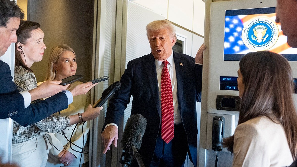 President Donald Trump wears a red tie standing while talking to the correspondents on the Air Force