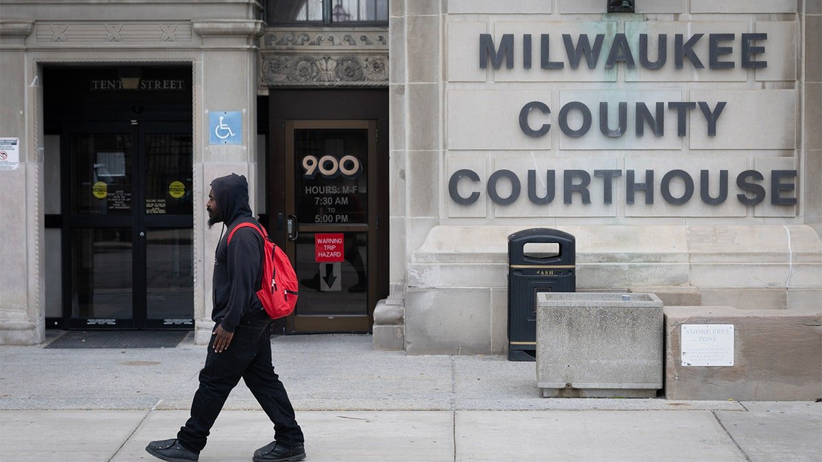 The pedestrians walk outside the Milwoke County Court, the federal judge's arrest site.