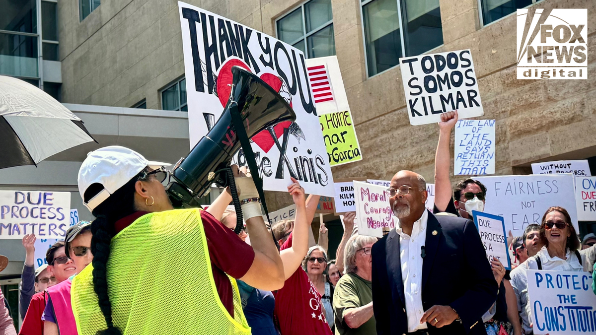 A woman is speaking through loudspeakers in a march outside the US District Court in Greenpelet, Maryland, where the demonstrators carry signs that support Kilmar Abrago Garcia and Judge Paula Shinis.