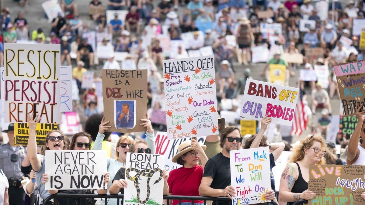 A large crowd of demonstrators carrying manually made in a public demonstration. Visible signs include slogans such as