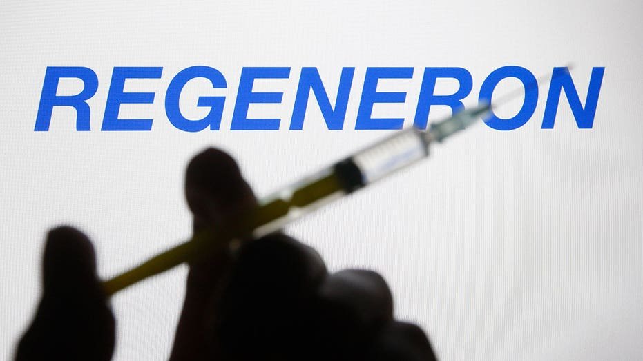 Ukraine - 2021/02/27: In this photography, the Regeneron Pharmaceuticals Logo of the American Biotechnology Company appears behind a silhouette with a medical syringe. (Clarification of photos by Pavlo Gonchaar/SOPA photos/Lightrockwal via Getty Images)