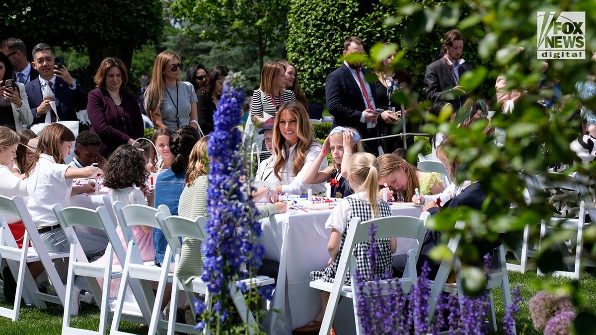 Flotus sits with children in the White House garden.