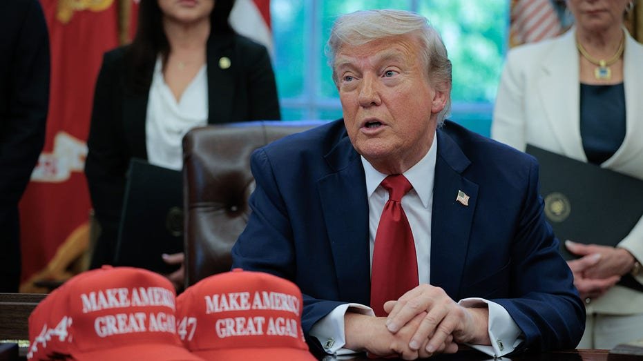 Trump is sitting behind the Oval Office office with Make Ameica, a wonderful red hats