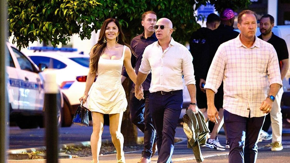 Lauren Sanchez wears a yellow dress and Ceff Bizos wears a white button and dark pants while walking outside his hands