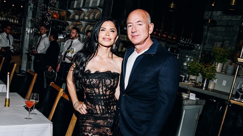 Lauren Sanchez wears a black lace dress and Jeff Bezos wears a marine color suit