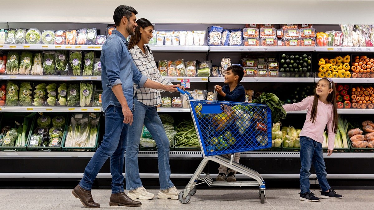 A family that uses a shopping cart while buying grocery in the supermarket