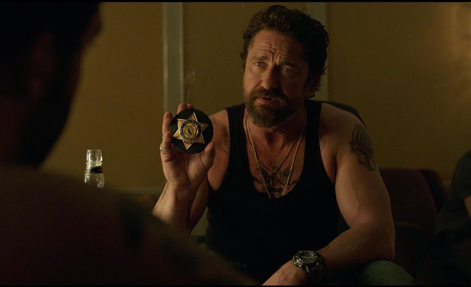 Gerard Batrler sits and holds the police badge in the thieves' den.
