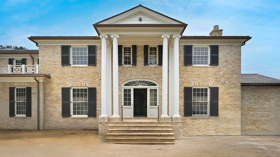 Tan Brick also includes black shutters and stone stairs that lead to anterior door.