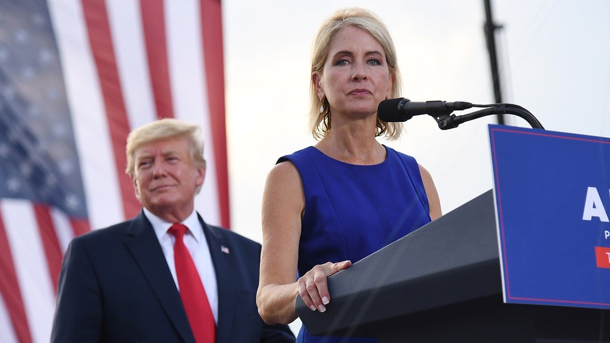 Representative Mary Miller in a blue dress in Lecterne, Trump, we know behind her