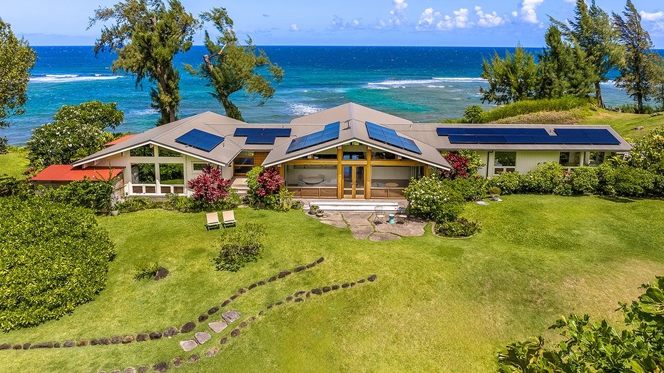 The house is surrounded by grass and lush green trees.