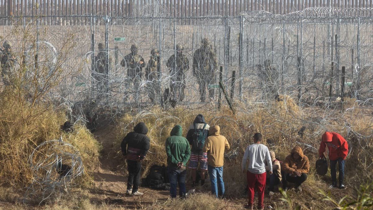 Immigrants are on the border, agents on another side of the fencing