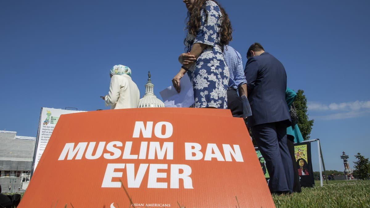 Activists gather in a park near the American Capitol, with an orange mark in the front reading
