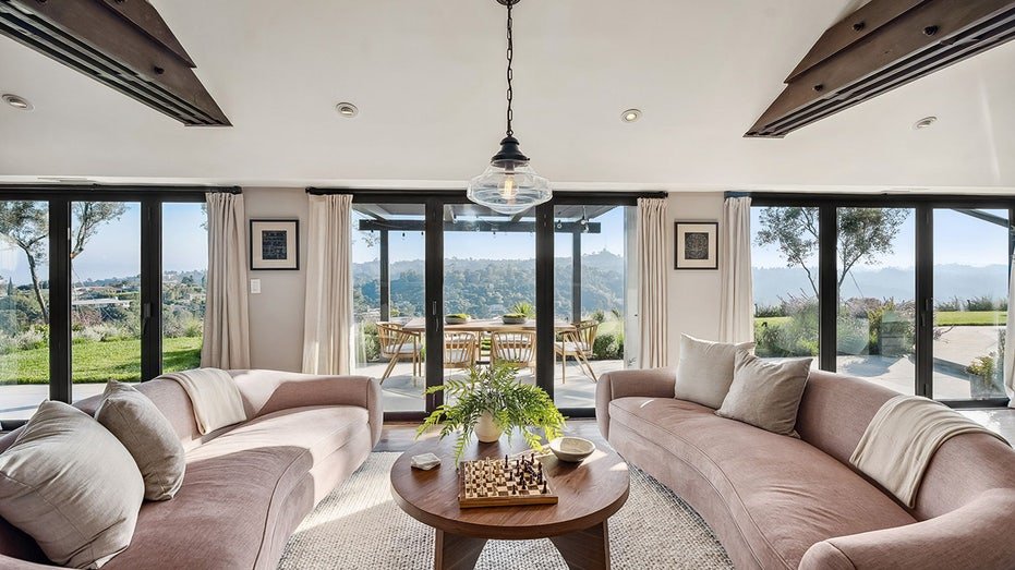 The family room features glass doors from floor to ceiling that open to the outdoor dining area.