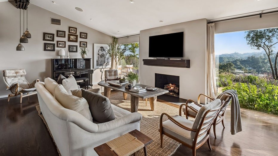 The living room features windows extending from floor to ceiling, stone fireplace and floors of dark solid wood.