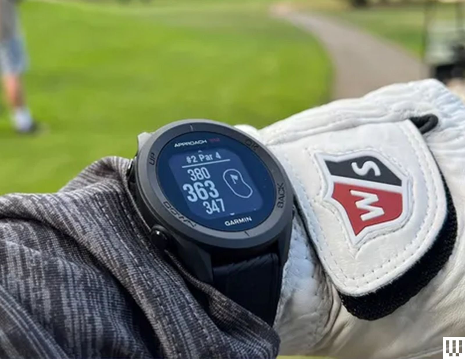 Garmin Fear S12 GPS GOLF Watch a digital wrist watch on a person's arm while wearing long gray sleeves and white golf ...