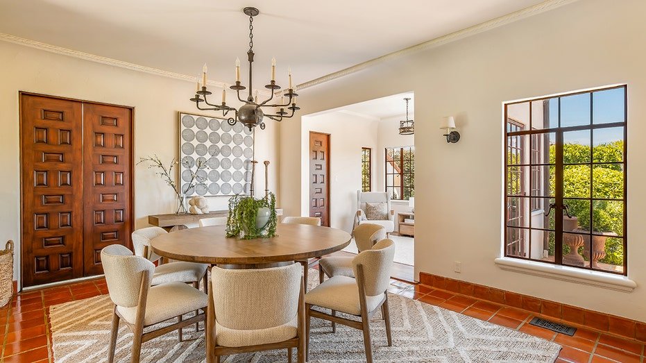 The dining room features a circular table and windows looking at the backyard.