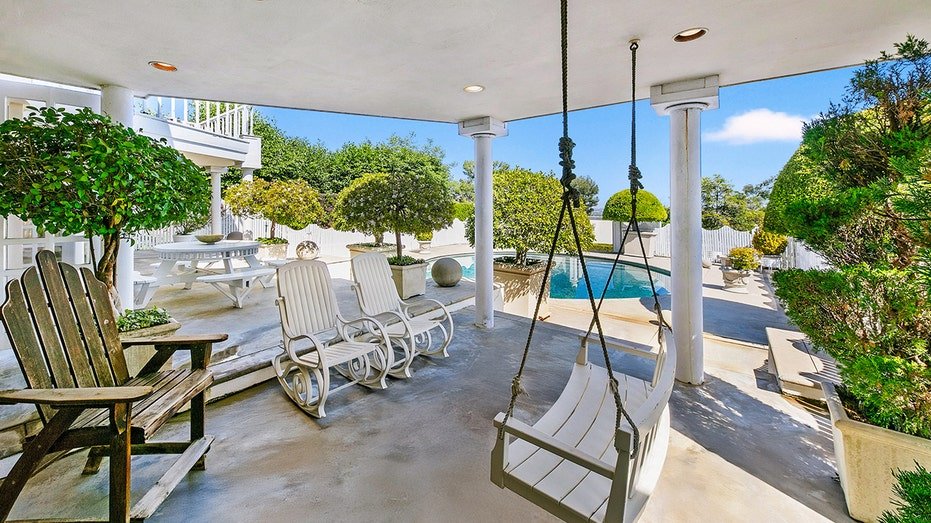 The backyard features a covered balcony with a swing.
