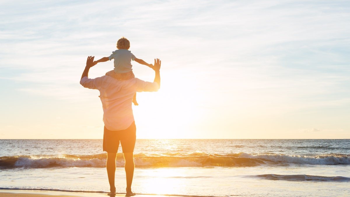 Father and Ibn Saeed enjoy playing on the beach at sunset. The concept of the father's family